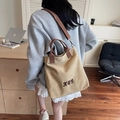 Sac fourre-tout en toile kaki avec bandoulière réglable et broderie porté par un mannequin - Kaki