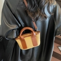 Mini sac cabas en toile et cuir marron porté par un mannequin avec un manteau noir - Khaki