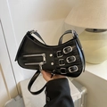 Black crescent shoulder bag with silver punk buckles and zippers in a minimalist setting - Black