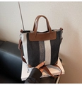 Détail d'un sac seau en toile à rayures noires et blanches et garniture en cuir marron - Noir