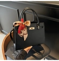 Détail d'un sac à main noir mat avec fermoir en métal et accessoire de foulard en soie - Noir