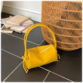 Détail d'un sac polochon jaune cylindrique avec texture brillante et boules métalliques - Jaune