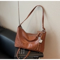 Detail view of retro brown PU leather shoulder bag with H.SHAY embossed logo and tassel - Brown