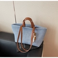 Detail of light blue canvas tote bag featuring brown leather handles and wooden bead charm - Denim Blue