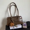 Dark brown high-gloss underarm bag with a plush teddy bear charm on white books - Brown (With Pendant)