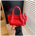 Detail of red pebble leather bucket bag featuring a bow and adjustable silver hardware - Red