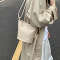 Fashionable woven bucket bag in beige with rustic beaded charm and long strap - Off-white