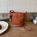 Chic brown woven bucket bag featuring unique wooden bead tassel and woven shoulder strap - Brown