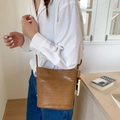 Brown woven bucket bag featuring cross-body strap and decorative bead charm - Khaki