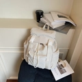 Mochila de viaje beige minimalista e impermeable con hebilla y cordón en un taburete - Blanco Roto