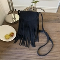 Close-up of black fringe crossbody bag with long tassels on a rustic wooden table - Black