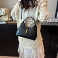 Elegante bolso hobo negro con detalles dorados llevado al hombro por una modelo - Negro