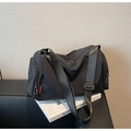 Detalle de bolsa de viaje de nailon negro con bolsillo lateral y etiqueta roja tejida - Negro