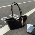 Large black woven leather tote bag with boho bead charm on asphalt street surface - Black