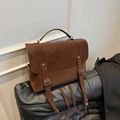 Vintage brown leather backpack with suede flap and metal buckle straps on black sofa - Brown