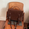 Dark brown vintage multi-purpose backpack with double buckle flap and top handle on wood chair - Brown