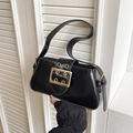 Black glossy shoulder bag featuring a large gold buckle and adjustable strap - Black