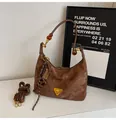 Brown leather bag detail featuring triangular metal plaque and beaded retro charms - Brown