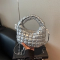 Sac à main matelassé argenté chic avec bandoulière sur un fond de livres de mode - Argenté