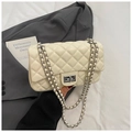 Detail shot of beige quilted handbag featuring silver chain strap and twist-lock clasp - White