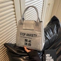 Silver Dupont paper handbag with Stop Anxiety text and grey webbing handles - Silver