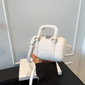 Modern white Boston bag with pebble leather texture and silver hardware held by hand - White