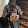 Brown PU leather backpack with butterfly buckle and plush bear charm shown on model - Coffee