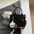 Elegant black textured leather crossbody bag with top handles and plush ball charm - Black