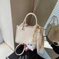 Chic beige crossbody bucket bag with textured finish and cute plush charm detail - Off-white