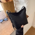 Minimalistische schwarze gewebte Beuteltasche mit Lederriemen auf einem Holztisch - Schwarz