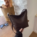 Dunkelbraune geflochtene Leder-Beuteltasche auf Holztisch im angesagten Retro-Stil - Braun