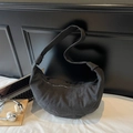 Minimalist black canvas croissant crescent bag with wide shoulder strap in daily office setting - Black