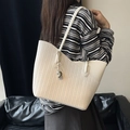 Chic beige woven tote bag with leather panels and silver charm detail on a model - Off-white