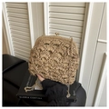 Detail van handgeweven strooien tas met gouden bolsluiting en golvend textuurpatroon - Khaki