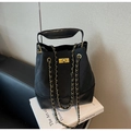Detail of black quilted leather bucket bag featuring gold metal swivel lock and chain straps - Black
