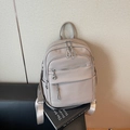 Taupe pebbled leather backpack with silver zippers and stylish tassel details - Castle Gray