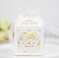 Macro shot of white laser-cut wedding favor box with Love heart pattern and silk ribbon - 5*5*8 CM / Ivory