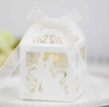 Close-up of white laser-cut wedding favor box with organza ribbon and couple silhouette - Ivory