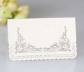 Detailed view of white pearl paper place card with hollow lace cut and silver scroll pattern - Ivory