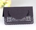 Close-up of black lace laser-cut table card with silver floral pattern on white background - Black