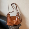 Caramel brown oil-wax leather shoulder bag with INBAG tag and tassel detail in warm lighting - Brown with Pendant
