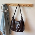 Retro deep brown glossy leather tote bag with flap closure on a wooden rack - Coffee No Charm