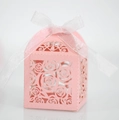 Close-up of pink laser-cut hollow rose candy gift box with elegant white ribbon bow - Pink
