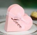 Rosa herzförmige Geschenkbox mit Love-Schriftzug und Schleife auf einem Teller - Rosa