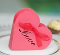 Detail der rosa herzförmigen Geschenkbox mit Love-Schriftzug und roter Seidenschleife - Perlrot