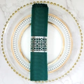 Flat lay of a silver geometric cut-out napkin ring with deep green linen napkin on a plate - Reflective Silver