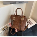 Detail of brown leather bucket bag with gold hardware and a floral bow charm - Brown (With Cherry Pendant)