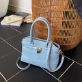 Light blue denim bucket bag with mini studs and gold lock on a chic textured floor - Blue