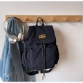 Detail of black nylon backpack with yellow embroidery hanging next to a denim jacket - Black