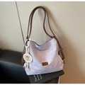 Detail of lavender canvas tote with brown leather strap resting on a black chair - Purple (With Charm)